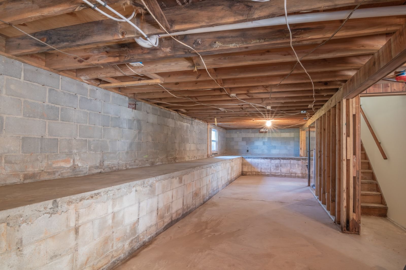 Unfinished basement with exposed framing and concrete block walls