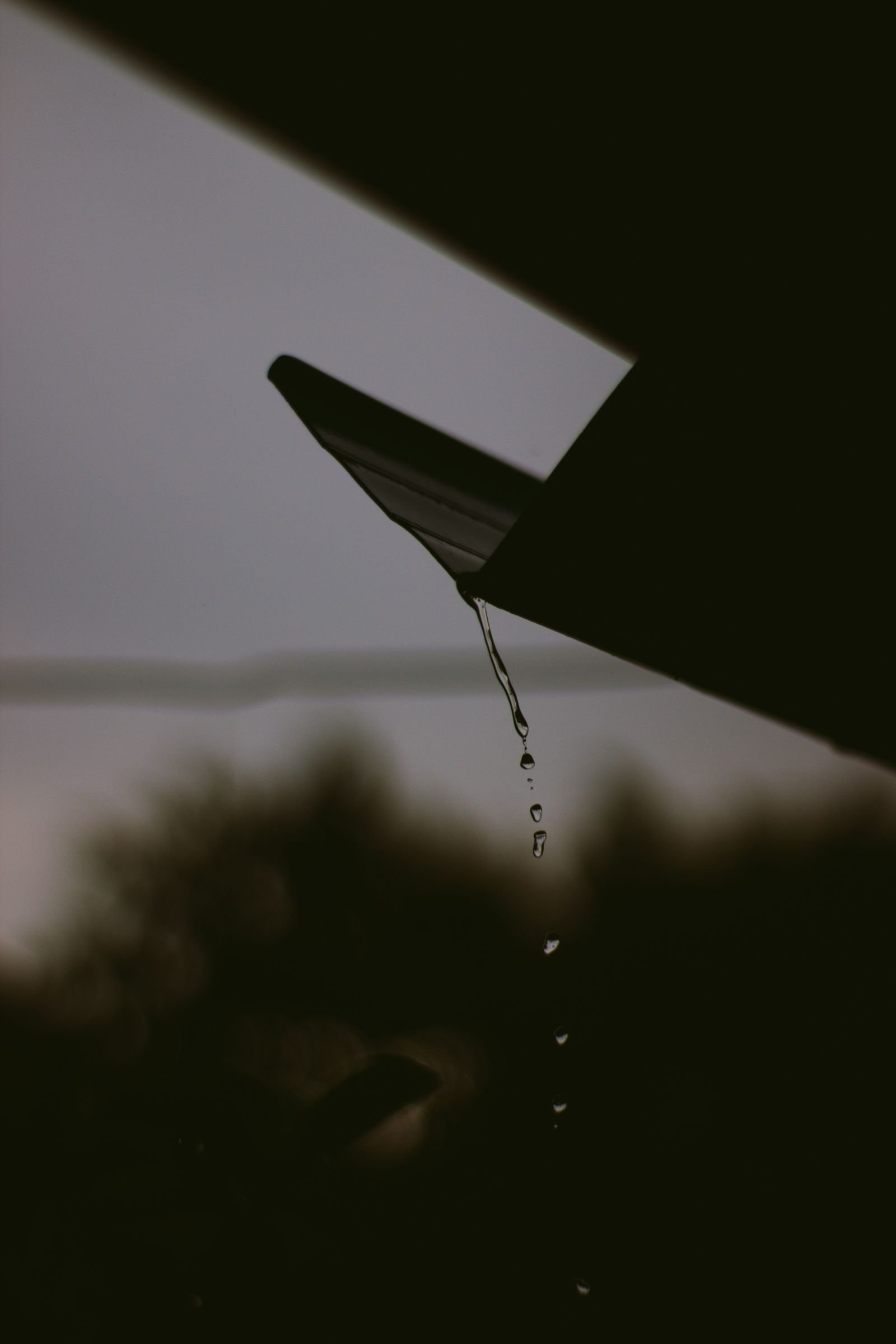 Rainwater cascading off a roof edge during a heavy storm